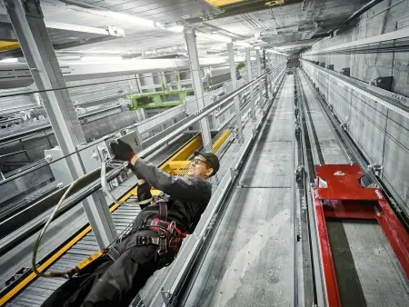 A TK Elevator technician performing elevator maintenance in an elevator hoistway.