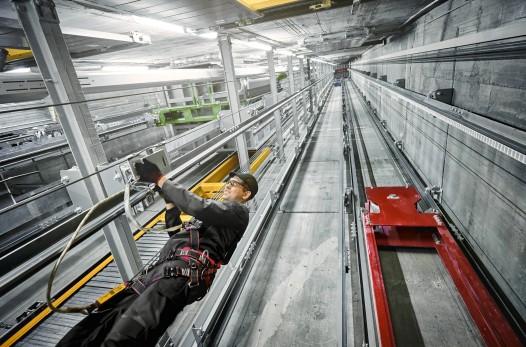 A TK Elevator technician performing elevator maintenance in an elevator hoistway.