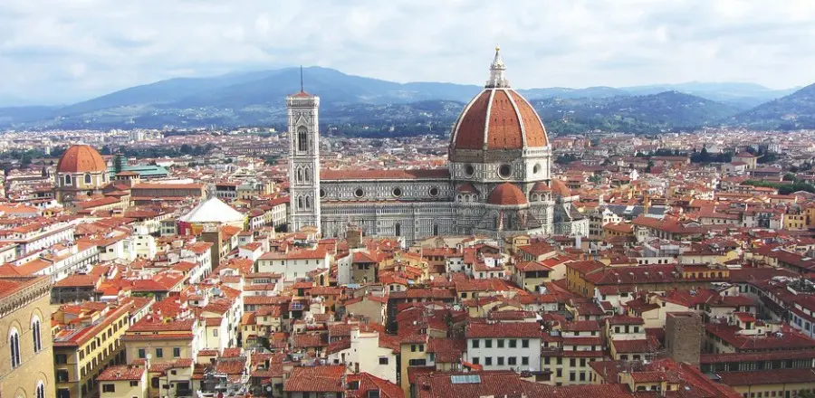 A view of the roofs of Florence, in Italy. The red tiles stand out against the blue backdrop of the sky.