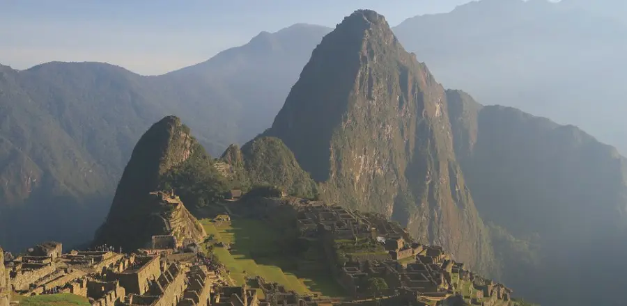 A montainous landscape with ruins at the bottom.