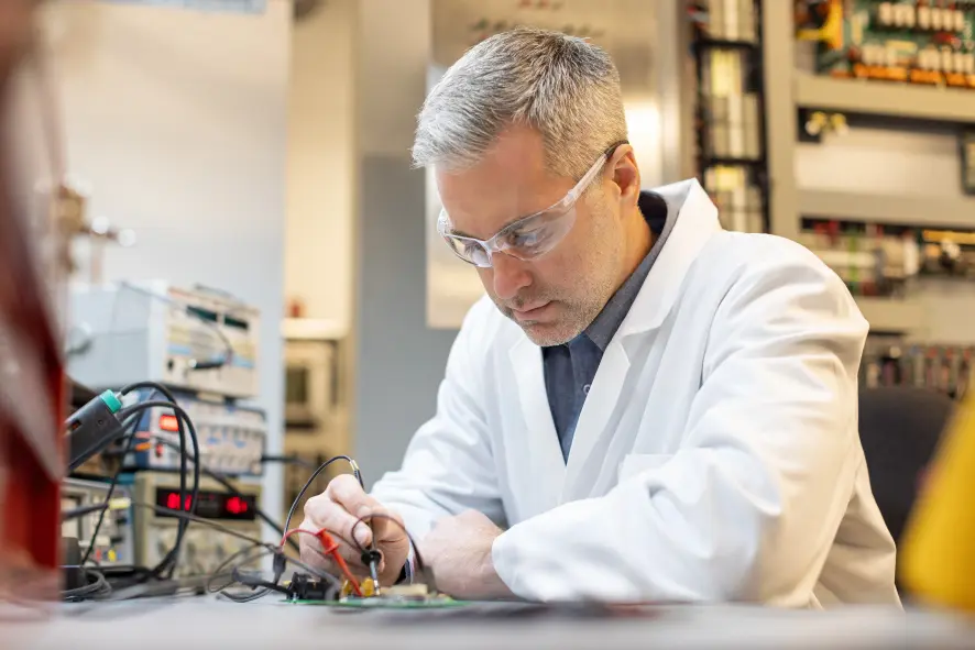 An engineer examining a computer board on a tabletop.