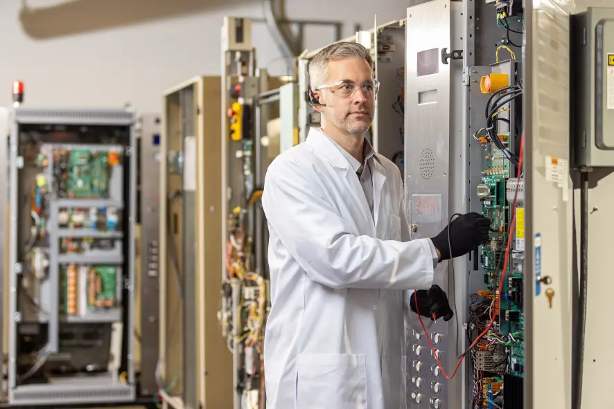 An engineer stands next to a controller with the access door open.