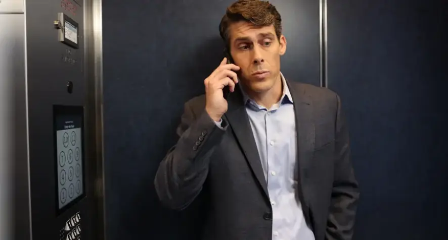 A man attempting to use a cell phone inside an elevator