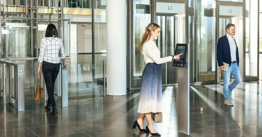 A photo of a woman using an AGILE kiosk to call her elevator