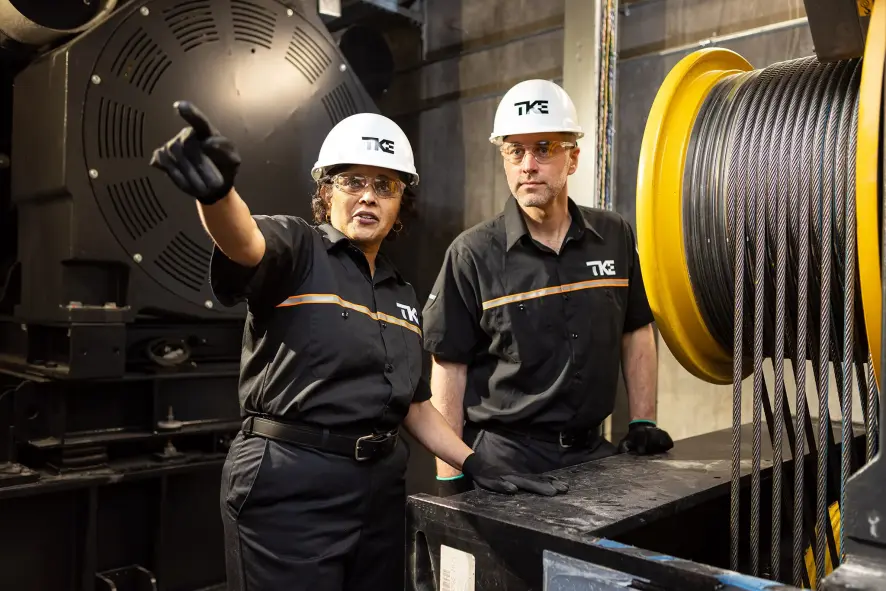Two technicians in an elevator machine room.