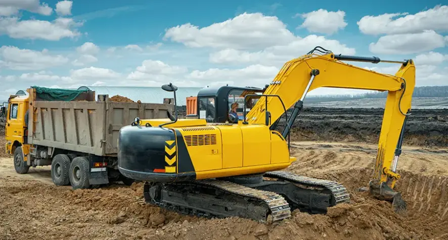 A large dump truck and an excavator on a work site.