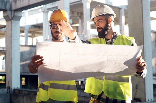 A pair of contractors look at plans on an active job site.