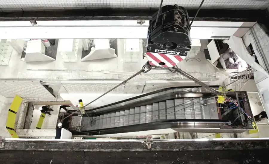 
An escalator being lowered into place by a crane.
